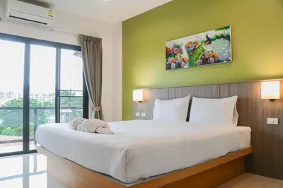 a bedroom with a large white bed with a large window at S2 Airport Residence in Nai Yang Beach