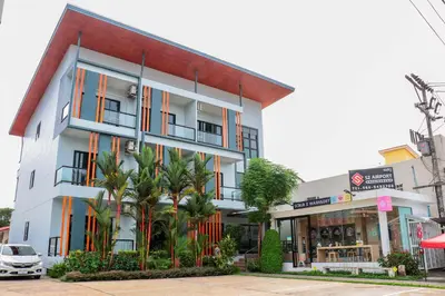 a building with palm trees in front of it at S2 Airport Residence in Nai Yang Beach