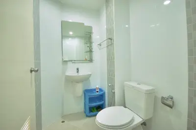 a white bathroom with a toilet and a sink at Risa Plus in Kathu