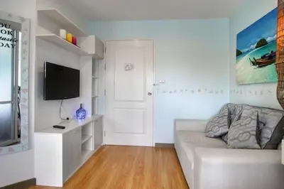 a living room with a white couch and a flat screen tv at Risa Plus in Kathu