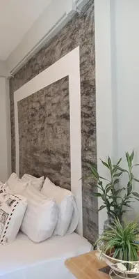a bed with white pillows and a brick wall at Eat n Sleep in Phuket Town