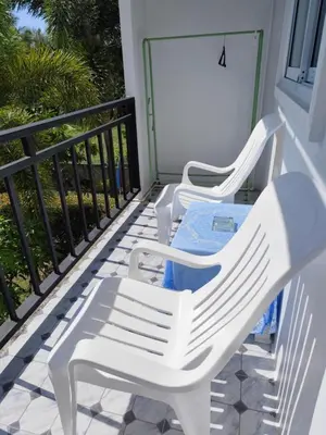 two white chairs sitting on a balcony at Bangtao Mango House in Bang Tao Beach