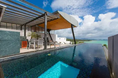 a swimming pool with a house with a view of the water at Aqua A1 in Rawai Beach