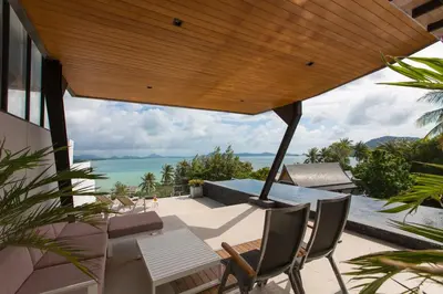 an outdoor patio with a table and chairs and the ocean at Aqua A1 in Rawai Beach