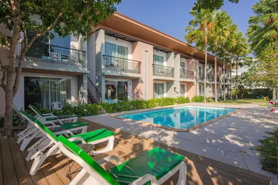 a resort with a swimming pool and chairs and a building at Parida Resort in Bang Tao Beach