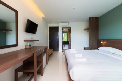 a bedroom with a bed and a desk and a mirror at Parida Resort in Bang Tao Beach