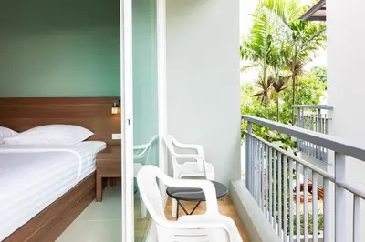 a bedroom with a bed and a balcony with palm trees at Parida Resort in Bang Tao Beach