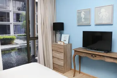 a bedroom with a bed and a television on a wooden table at Baan Mai Khao in Mai Khao Beach