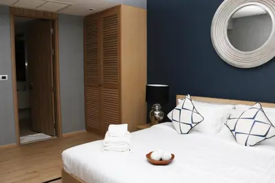 a bedroom with a white bed with a mirror at Baan Mai Khao in Mai Khao Beach