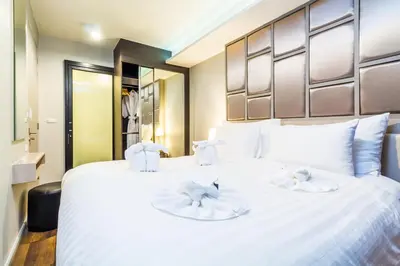a bedroom with a large white bed with two towels at 6th Avenue Surin by Lofty in Surin Beach