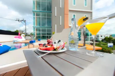 a table with a plate of fruit and a drink at The Elysium Residence - SHA Extra Plus in Chalong