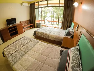 a hotel room with two beds and a television at Madam House in Karon Beach