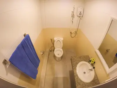 a small bathroom with a toilet and a blue towel at Madam House in Karon Beach