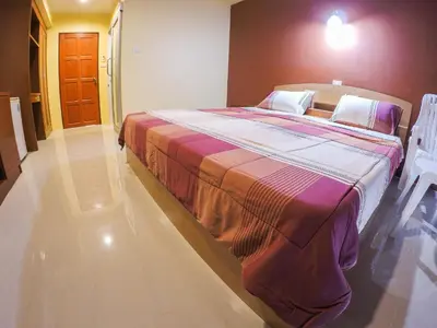 a large bed in a room with two white chairs at Madam House in Karon Beach