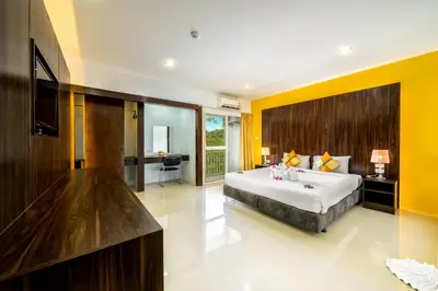 a bedroom with a large bed and yellow walls at Naiyang Place - Phuket Airport in Nai Yang Beach
