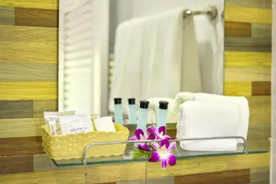a bathroom with a glass shelf with towels and a flower at Naiyang Place - Phuket Airport in Nai Yang Beach