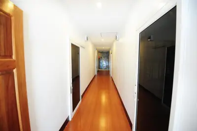 a hallway with a long corridor with white walls and wood floors at Twin Palms Hostel Phi Phi in Phi Phi Don