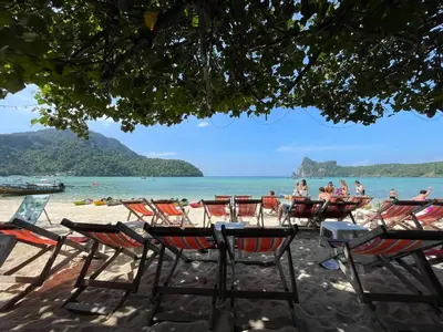 a group of chairs and tables on a beach at Twin Palms Hostel Phi Phi in Phi Phi Don