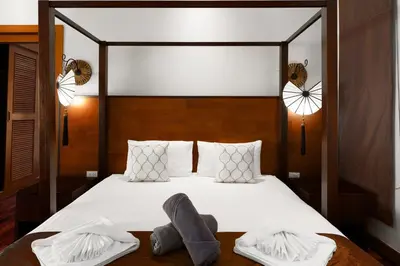 a bedroom with a bed with white sheets and two slippers at Emotion 2 Villa by G Estate in Rawai Beach
