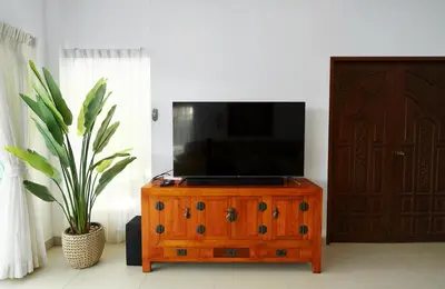a television on top of a wooden dresser with a plant at La Romanee Infinity by G Estate in Rawai Beach