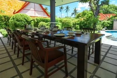 a long wooden table and chairs on a patio at La Romanee Infinity by G Estate in Rawai Beach