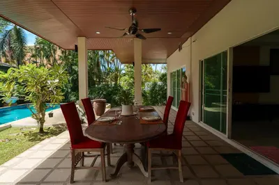 a wooden table and chairs on a patio at Corton Villa by G Estate in Rawai Beach