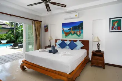 a bedroom with a large bed and a pool at Corton Villa by G Estate in Rawai Beach