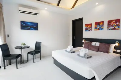 a bedroom with a bed and a table and chairs at Clos Vougeot Villa by G Estate in Rawai Beach