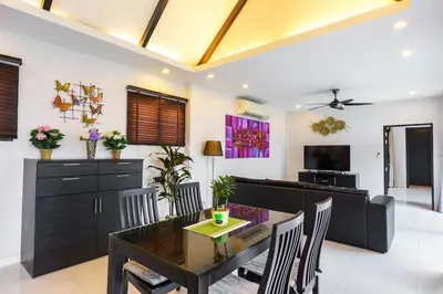 a dining room and living room with a table and chairs at Clos Vougeot Villa by G Estate in Rawai Beach