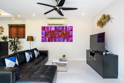 a living room with a black couch and a ceiling fan at Clos Vougeot Villa by G Estate in Rawai Beach