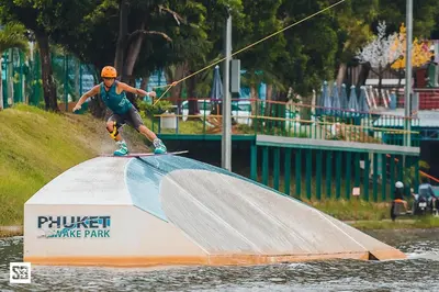 a man riding a surfboard on a ramp in the water at Phuket Wake Park in Kathu