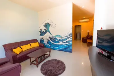 a living room with a couch and a painting of a wave at Phuket Wake Park in Kathu