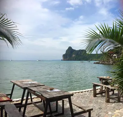 two picnic tables sitting next to a body of water at Sunflower Boathouse in Phi Phi Don