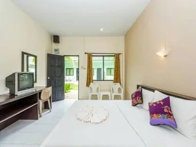 a bedroom with a large white bed with a television at Baantonsai Garden Resort in Patong Beach