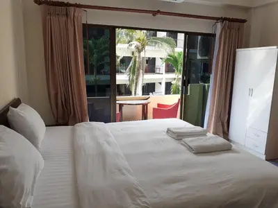 a bedroom with a white bed with a large window at NB House in Karon Beach
