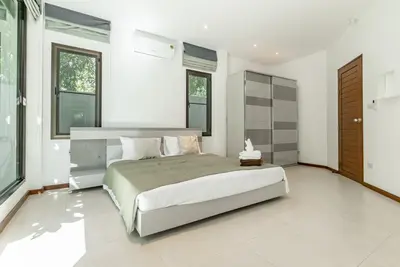 a bedroom with a large bed and some windows at Villa Andre by VillaCarte in Nai Harn Beach