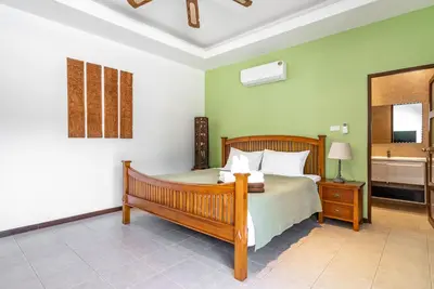 a bedroom with a bed in a room with green walls at Villa Andre by VillaCarte in Nai Harn Beach