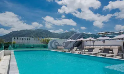 a swimming pool with chairs and umbrellas on top of a building at The Bloc Hotel Phuket in Patong Beach