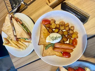 two plates of food with a sandwich and french fries at The Bloc Hotel Phuket in Patong Beach