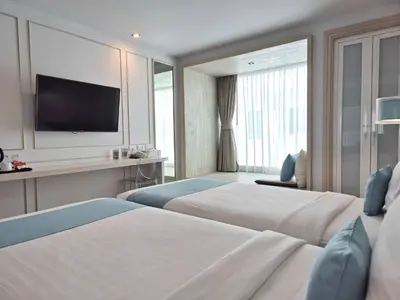 a hotel room with two beds and a flat screen tv at The Bloc Hotel Phuket in Patong Beach
