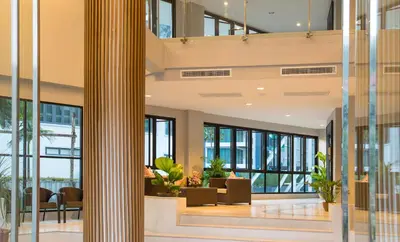 a lobby of a building with glass walls and a column at AVA SEA Resort Krabi, Ao Nang Beach in Ao Nang Beach