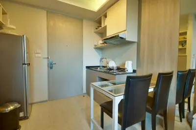 a kitchen with a table and chairs and a refrigerator at 6th Avenue Surin by Risa in Surin Beach