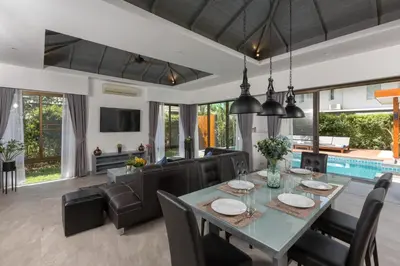 a dining room and living room with a table and chairs at Karon Beach Pool Villa - Sha Extra Plus in Karon Beach