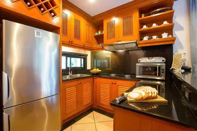 a kitchen with wooden cabinets and a stainless steel refrigerator at VILLA PAGAI Pool Baan Bua Estate Naiharn in Rawai Beach