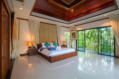 a bedroom with a large bed in a room with windows at VILLA PAGAI Pool Baan Bua Estate Naiharn in Rawai Beach