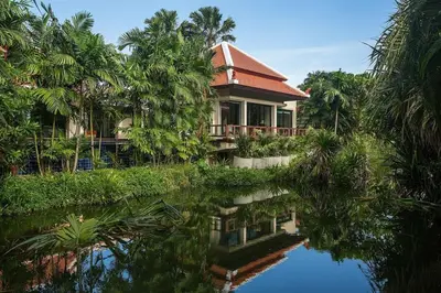 a house with a red roof next to a body of water at VILLA PAGAI Pool Baan Bua Estate Naiharn in Rawai Beach