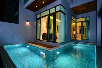 a house with a swimming pool in front of a house at Bukit Pool Villas - SHA Extra Plus in Patong Beach
