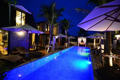 a swimming pool at night with umbrellas and chairs at Bukit Pool Villas - SHA Extra Plus in Patong Beach