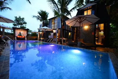 a large swimming pool with umbrellas next to a building at Bukit Pool Villas - SHA Extra Plus in Patong Beach