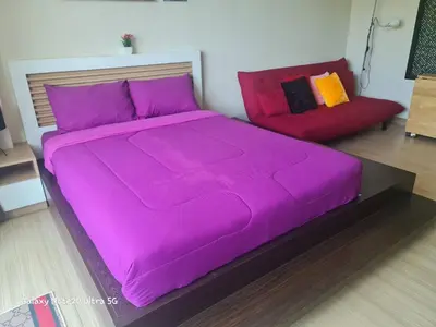 a purple bed and a red couch in a room at The Naithorn Condo Unit 401 in Nai Thon Beach